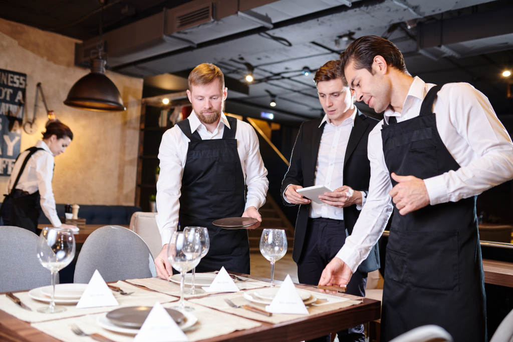 Serious banquet manager and waiters serving tables for event